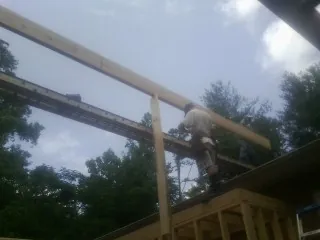 Carpenter setting a ridge beam over a new addition frame — Ice Dam Removal by Roofing Brothers in Penrose